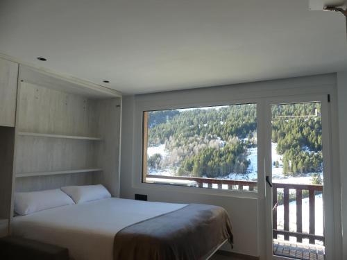 ein Schlafzimmer mit einem Bett und einem großen Fenster in der Unterkunft Ideal per una escapada in Bordes d´Envalira 