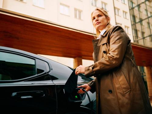 a woman in a trench coat standing next to a car at Clarion Hotel Stockholm in Stockholm
