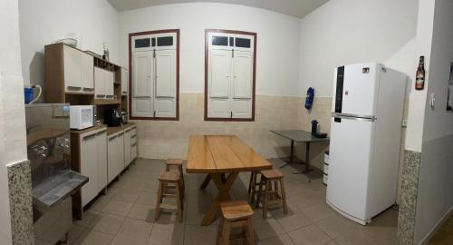 kuchnia z drewnianym stołem i lodówką w obiekcie Quarto inteiro, próx ao Centro - República Saideira w mieście Ouro Preto