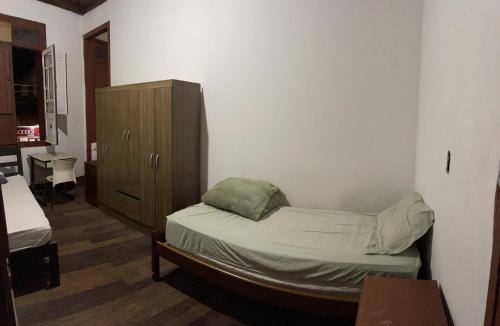 1 dormitorio pequeño con 1 cama y armario de madera en Quarto inteiro, próx ao Centro - República Saideira en Ouro Preto