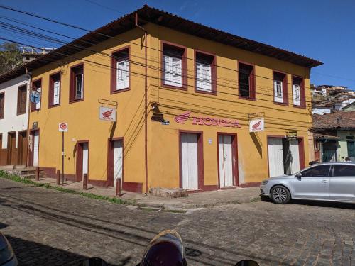 żółty budynek z samochodem zaparkowanym przed nim w obiekcie Quarto inteiro, próx ao Centro - República Saideira w mieście Ouro Preto