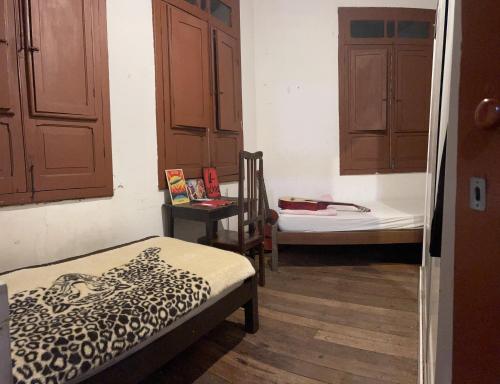 um quarto com uma cama, uma cadeira e armários em Quarto inteiro, próx ao Centro - República Saideira em Ouro Preto