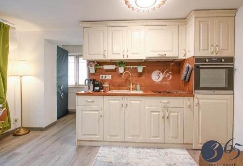 a kitchen with white cabinets and a sink at 365 Guest House in Hunedoara