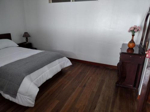 a bedroom with a bed and a table with a vase on it at Acogedor Departamento Central in Loja