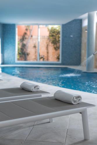 two towels sitting on a bench in front of a swimming pool at Sagitario Playa in Cala Blanca