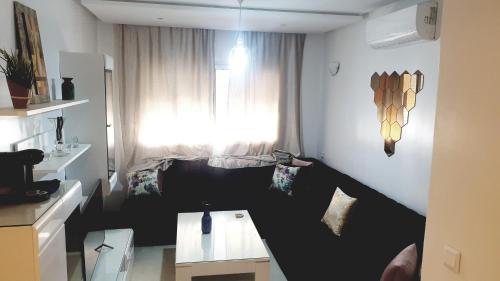 ein kleines Wohnzimmer mit einem Fenster und einem Tisch in der Unterkunft Coralia Haut Standing Appart f2 in Oujda