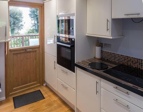 a kitchen with white cabinets and a sink and a window at Chalet Thirteen in Deal