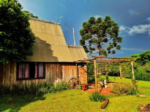 una vecchia casa in legno con un albero sullo sfondo di Cabana/Sítio em meio a Natureza Chalé da Collina a Sertão