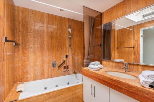 une salle de bain avec un lavabo, un miroir et une baignoire dans l'établissement Le Lucior - FLBK conciergerie, à Cannes