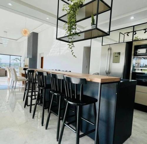 a kitchen with a bar with black bar stools at Casa Alto Padrão Represa de Itupararanga Ibíuna in Sorocaba