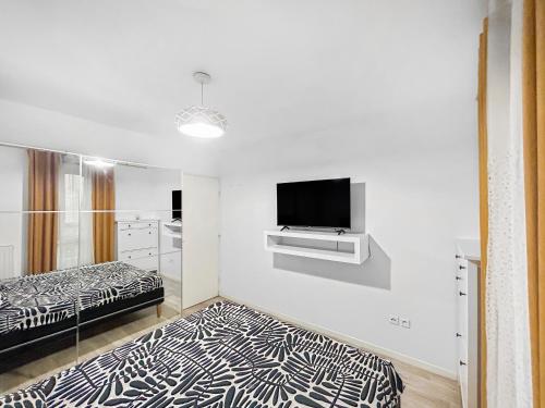 une chambre blanche avec deux lits et une télévision à écran plat dans l'établissement Sérénité Urbaine Aubervilliers, à Aubervilliers