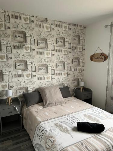 a bedroom with a bed and a wall covered in pictures at Petite maison au calme in Poupry