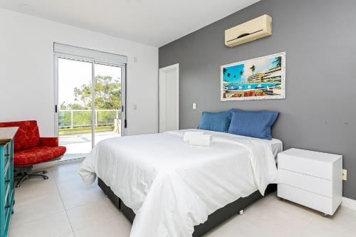 a bedroom with a bed and a red chair at Apto cobertura com vista p/ mar, Floripa ASR304 in Florianópolis