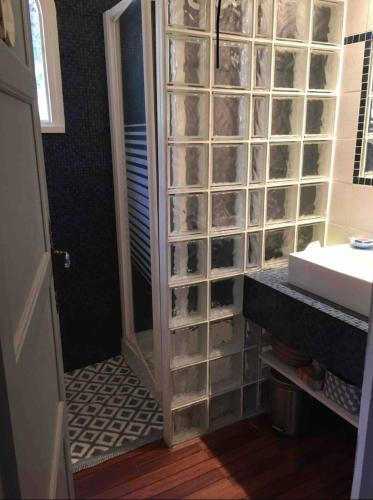 La salle de bains est pourvue d'une paroi en verre à côté d'un lavabo. dans l'établissement Coeur de Collioure - Parking - Rez de jardin, à Collioure