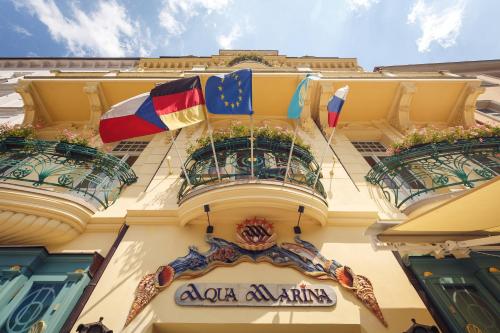 カルロヴィ・ヴァリにあるアクア マリーナの二つのバルコニーに旗が掲げられた建物