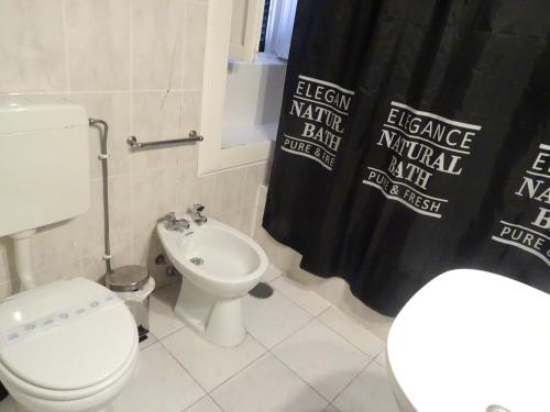 a bathroom with a white toilet and a black shower curtain at Hotel Monte Carlo in Funchal