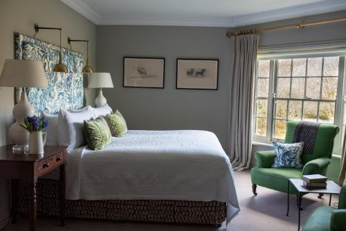 a bedroom with a bed and a green chair at Gregans Castle Hotel in Ballyvaughan