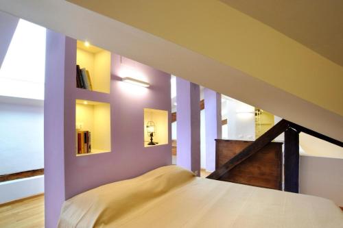 a bedroom with purple walls and a staircase with a bed at SM Hospitality SANTO STEFANO in Reggio Emilia