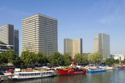 a group of boats docked in a river with tall buildings at Mercure Paris Bercy Bibliothèque in Paris