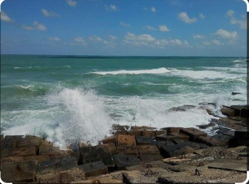 una ola chocando en una playa rocosa cerca del océano en SUN SEA HOLIDAy, en Alejandría