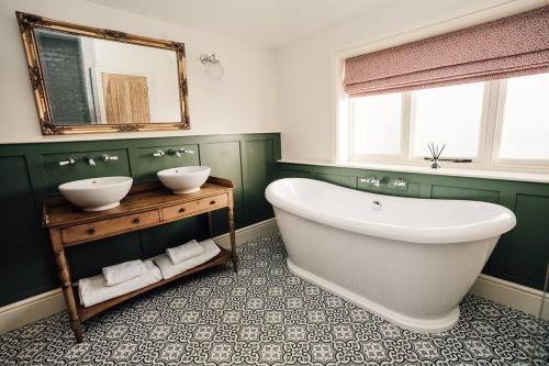 baño con bañera blanca grande y 2 lavabos en Luxury Farm Cottage with Hot Tub, en Northallerton