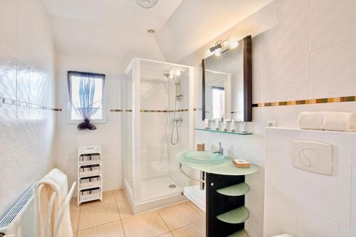 uma casa de banho branca com um lavatório e um chuveiro em Havre de paix avec piscine pour 6 personnes em Pornichet