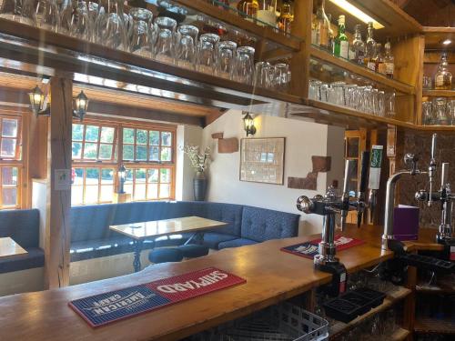 um restaurante com um bar com copos na parede em The Mill Forge em Gretna Green