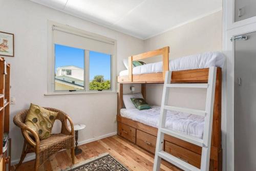 a bedroom with two bunk beds and a window at Beach Bach on the Dune Trails in Tirohanga