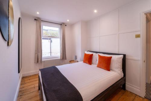 a bedroom with a large white bed with orange pillows at Elegant 3 bedroom home in the centre of Cheltenham in Cheltenham