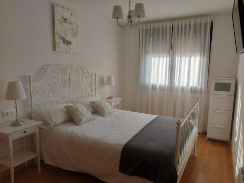 een witte slaapkamer met een wit bed en een raam bij Piso do Espolón in Padrón