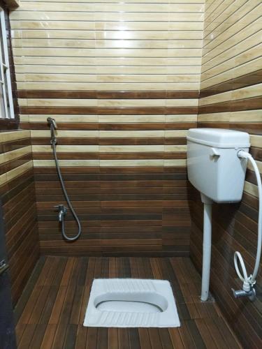 a bathroom with a toilet and a wooden floor at Hotel Hari Gayatri Regent in Guwahati