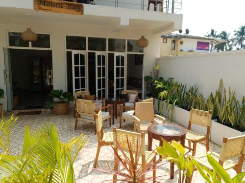 a patio with chairs and tables on a building at Mount Bay Guest House in Mount Lavinia