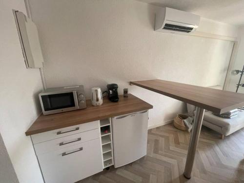 een keuken met een bureau, een magnetron en een tafel bij Appartement Cap d'Agde dans résidence avec piscine in Cap d'Agde