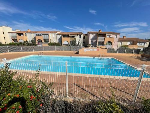 una piscina con valla y algunas casas en Appartement Cap d'Agde dans résidence avec piscine, en Cap d'Agde