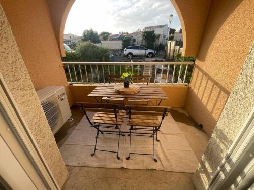 balcón con mesa y sillas en Appartement Cap d'Agde dans résidence avec piscine en Cap d'Agde