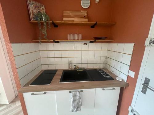 a kitchen with a sink and a tiled wall at Appartement Cap d'Agde dans résidence avec piscine in Cap d'Agde