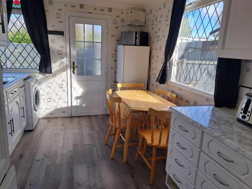 a kitchen with a table and chairs and a refrigerator at Beach & Tonic beachside chalet in Humberston