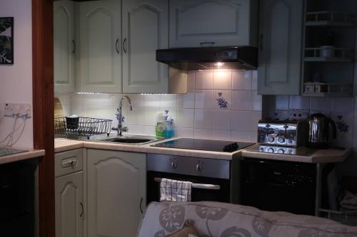 a kitchen with white cabinets and a stove top oven at Cosy 2-bedroom cottage in the Lake District in Bowness-on-Windermere