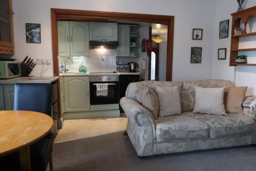 a living room with a couch and a kitchen at Cosy 2-bedroom cottage in the Lake District in Bowness-on-Windermere