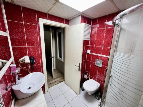 a bathroom with a toilet and a sink and red tiles at Otel Madi in Seyhan