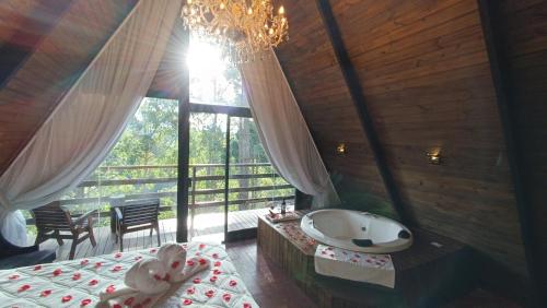 a large bathroom with a tub and a large window at Chalé Capivari Esmeralda in Campos do Jordão