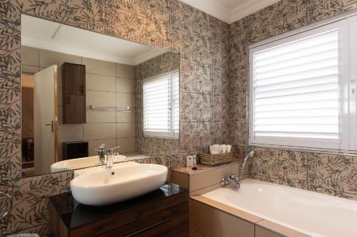 een badkamer met een wastafel, een bad en een spiegel bij Owls Nest Self Catering in George