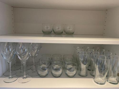 a bunch of wine glasses sitting on a shelf at 5 bedroom detached house sleeps 13 spacious Parking 5 mins driving to Bicester Village in Bicester