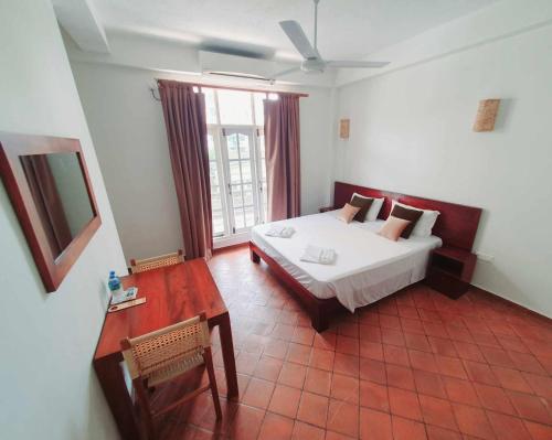 a bedroom with a bed and a table and a window at MountBaylk in Mount Lavinia