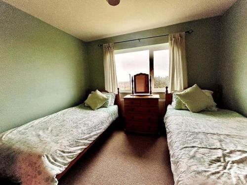 1 Schlafzimmer mit 2 Betten, einem Spiegel und einem Fenster in der Unterkunft Ballinskelligs Coastal Sanctuary in Ballinskelligs