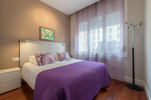 - une chambre avec un lit violet et une fenêtre dans l'établissement Gran Vía 55 Exclusive Apartments, à Madrid