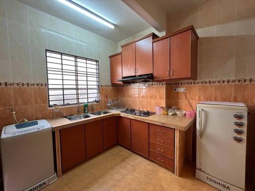 uma cozinha com armários castanhos e um frigorífico branco em Homestay Jitra Zultie's em Jitra