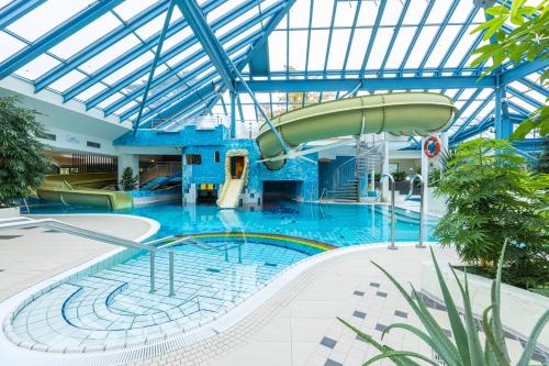 - une grande piscine avec toboggan dans un bâtiment dans l'établissement IFA Rügen Hotel & Ferienpark, à Binz