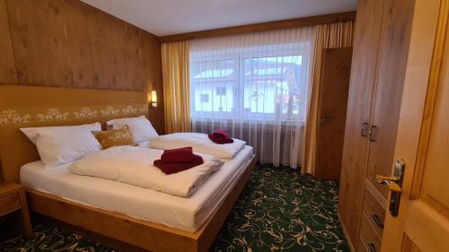 a bedroom with a bed with white sheets and a window at Appartement Auszeit in Holzgau