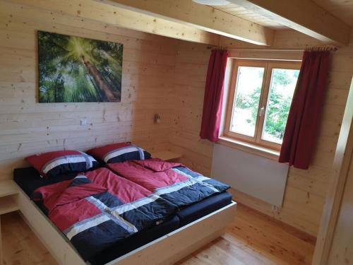 ein Schlafzimmer mit einem Bett in einem Blockhaus in der Unterkunft Klippitzstern House 2 in Klippitztorl